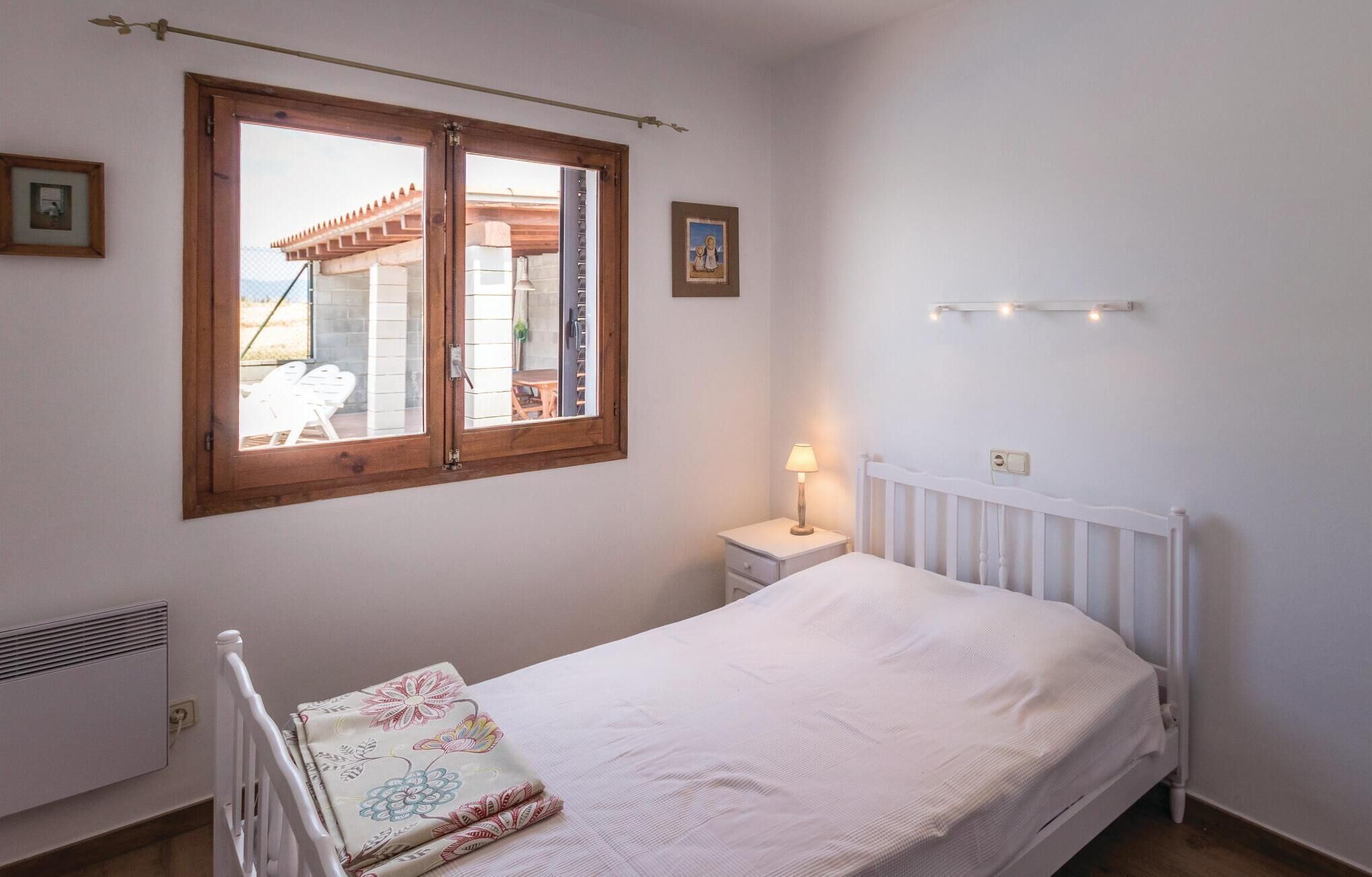 A bedroom with a single bed, a nightstand, a window with a view of an outdoor terrace, and a radiator.