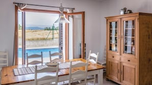 Un coin repas avec une table et des chaises en bois, un buffet et une vue sur une piscine, visible à travers des portes vitrées.