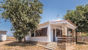 Une petite maison de plain-pied, avec des fondations en pierre, un toit en tuiles et une porte en bois.