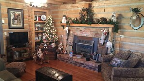 Interior acogedor de una cabaña de troncos con chimenea, un árbol de Navidad y decoración rústica.