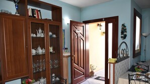 A dining area with a table set for four, a wooden cabinet with glass doors, and a door marked "WELCOME". - Il Girasole (Assemini)