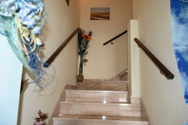 A staircase with marble steps, wooden handrails, and a wall-mounted picture.