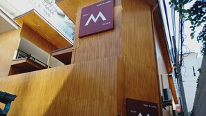 Puinen julkisivu, jossa on suuri «M»-logo ja teksti, joka kertoo, että kyseessä on «Resort Bangkok» -hotelli.
