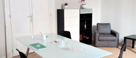 Una sala de estar moderna con un sofá blanco, un sillón gris, una mesa de centro de vidrio y una lámpara de pie.