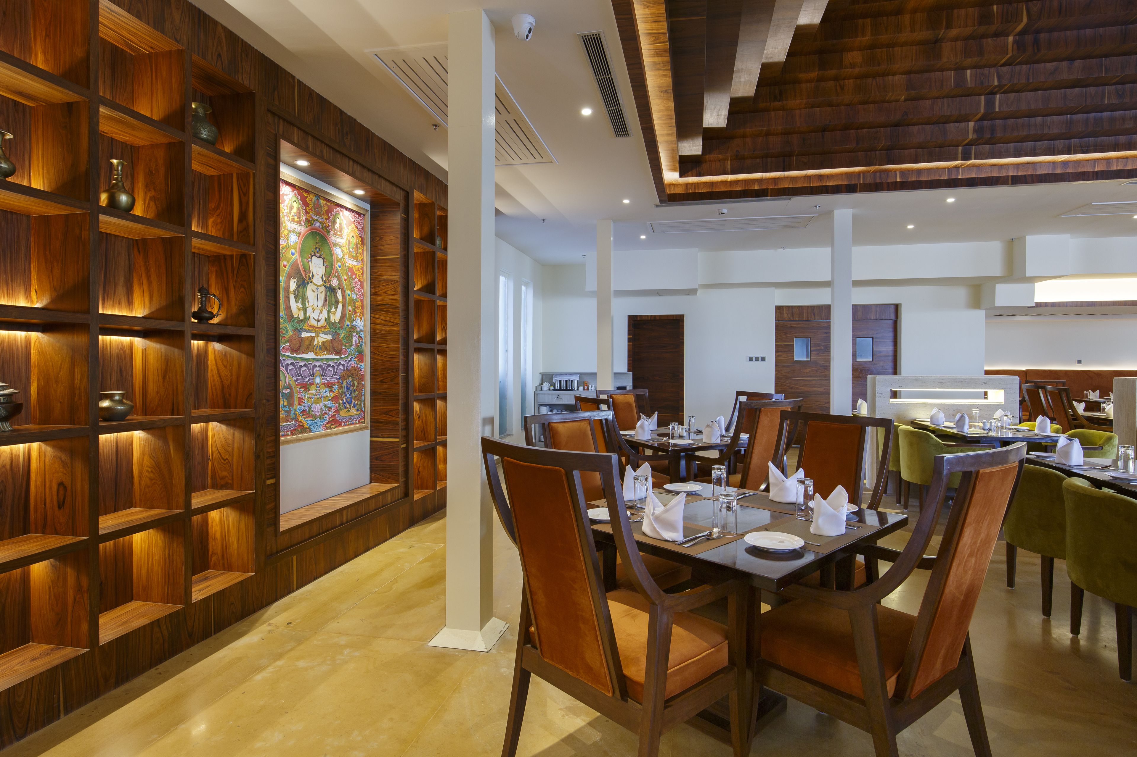 A dining area with wooden paneling, a large decorative painting, and multiple dining tables with chairs.
