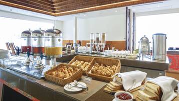 A buffet with various food items, including bread, pastries, and condiments.
