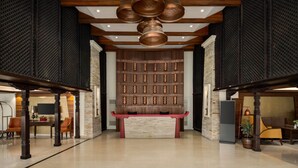 A spacious lobby with a central reception desk, wooden beams, and a patterned wall. - Ramada by Wyndham Kathmandu Dhumbarahi (Kathmandu)