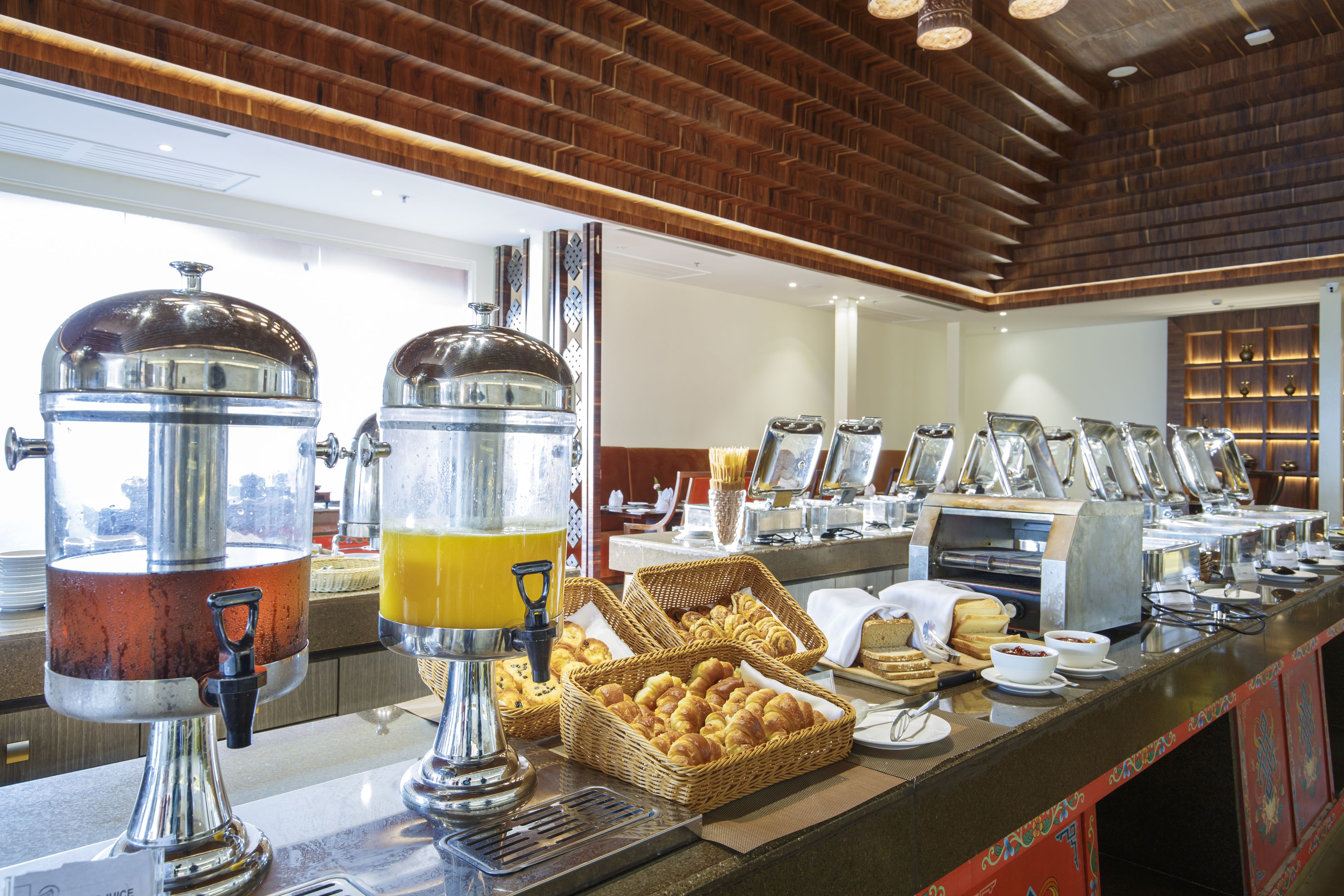 Montaje de bufé con varias estaciones de comida, que incluye un dispensador de zumo y cestas de pastelería.