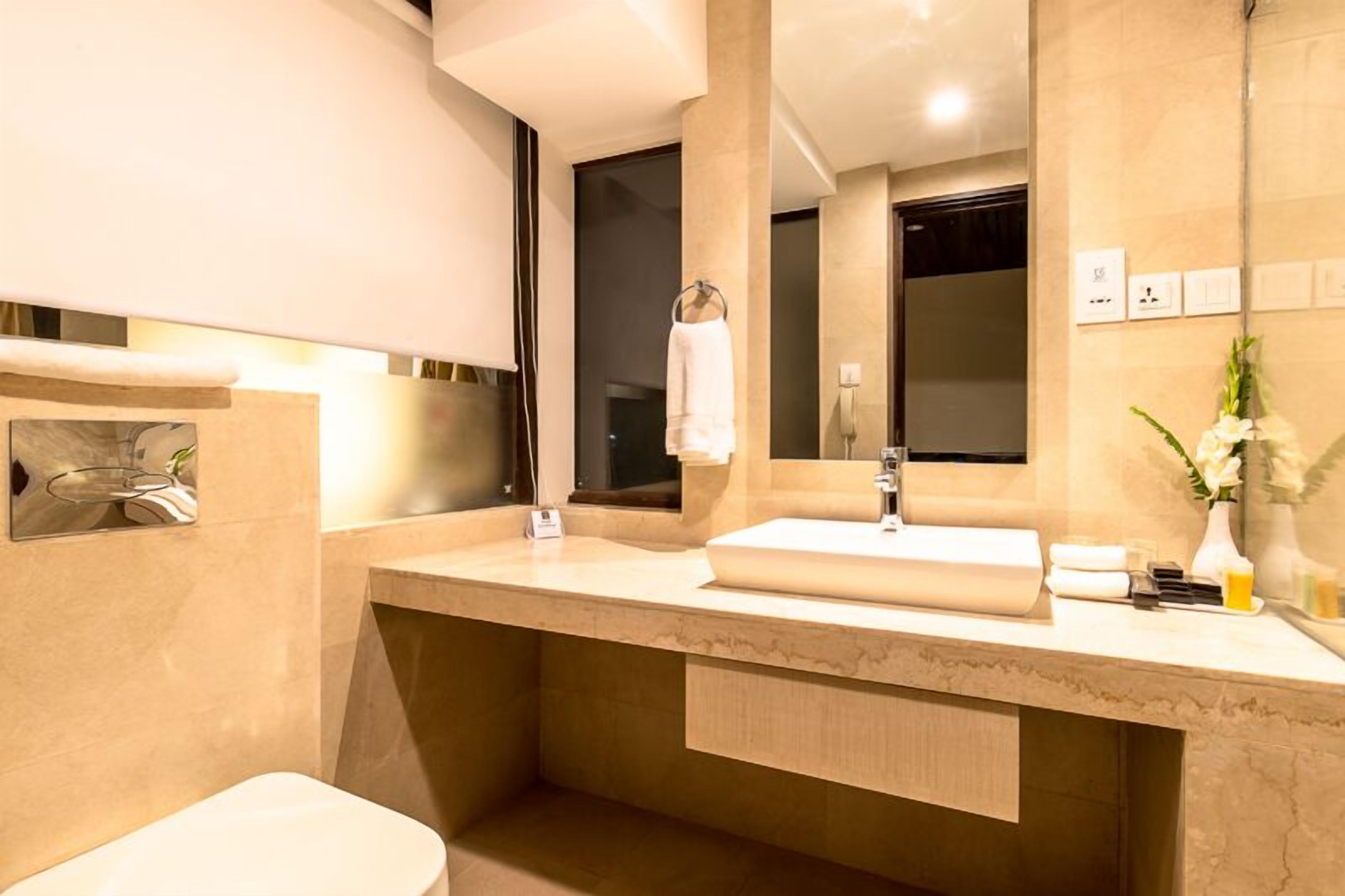 A modern bathroom with a large mirror, a sink, and a toilet.