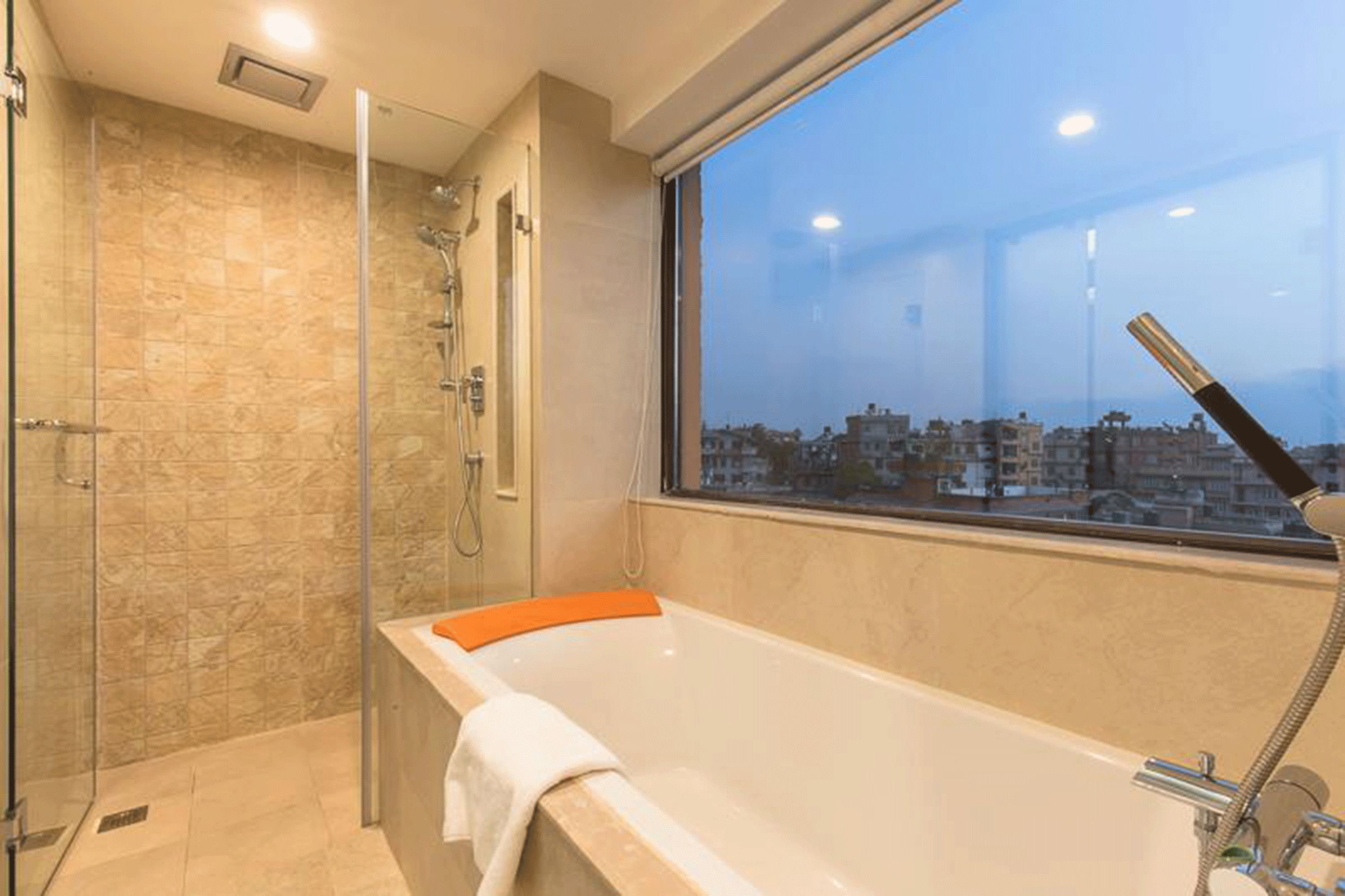 Ein modernes Badezimmer mit einer Badewanne, einer Dusche und einem großen Fenster mit Blick auf die Stadt.