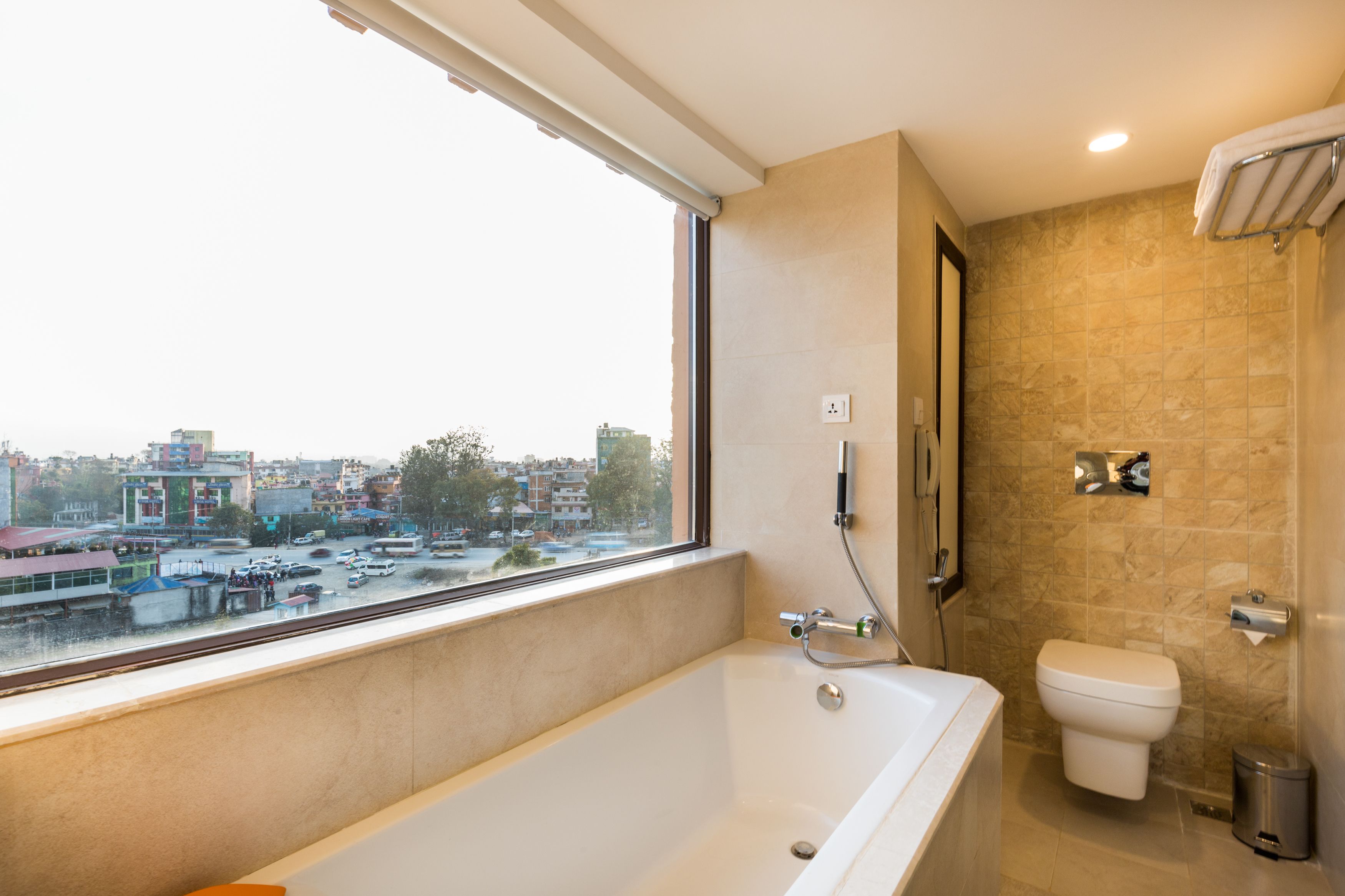 Un baño moderno con bañera, inodoro y ventana con vistas a la ciudad.