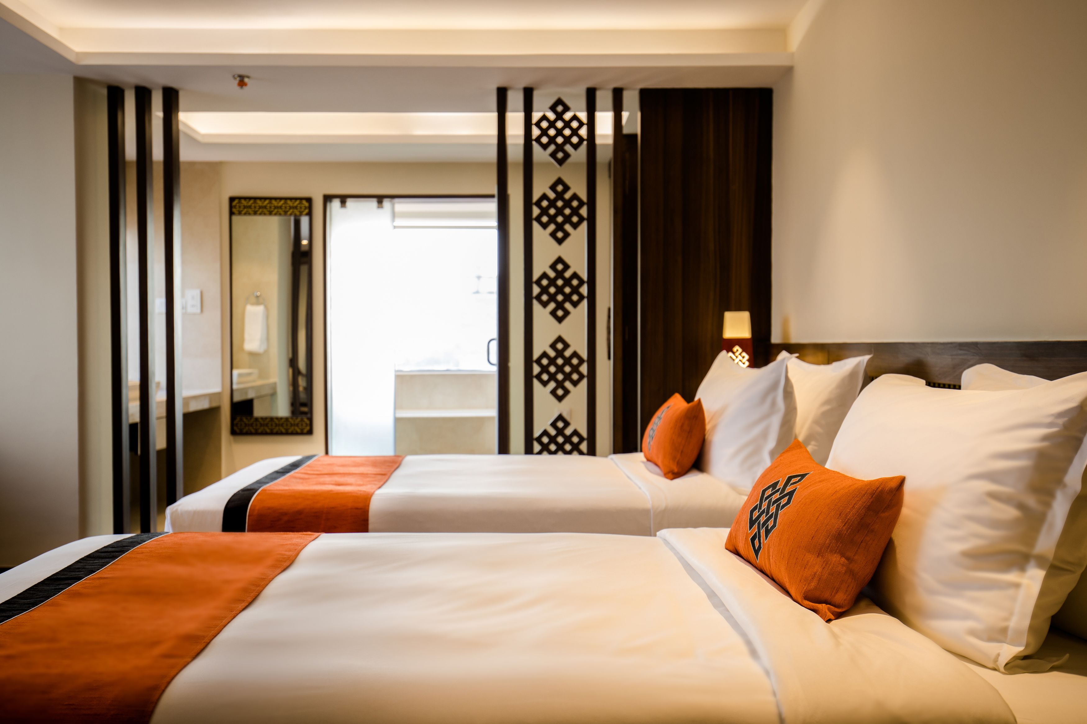 A hotel room with two beds, a bathroom, and a view of the outside.