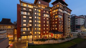 A multi-story hotel with a prominent 'RAMADA' sign, featuring a modern architectural design with a mix of stone and brick facades, and a well-lit entrance area. - Ramada by Wyndham Kathmandu Dhumbarahi (Kathmandu)