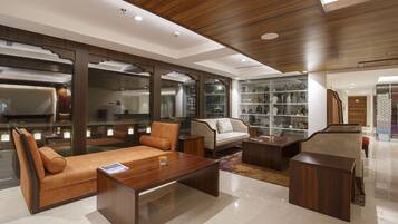 Una sala de estar moderna con un sofá, sillones, una mesa de centro y una estantería.