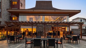 An outdoor dining area with tables and chairs, a covered seating area, and a bar. - Ramada by Wyndham Kathmandu Dhumbarahi (Kathmandu)