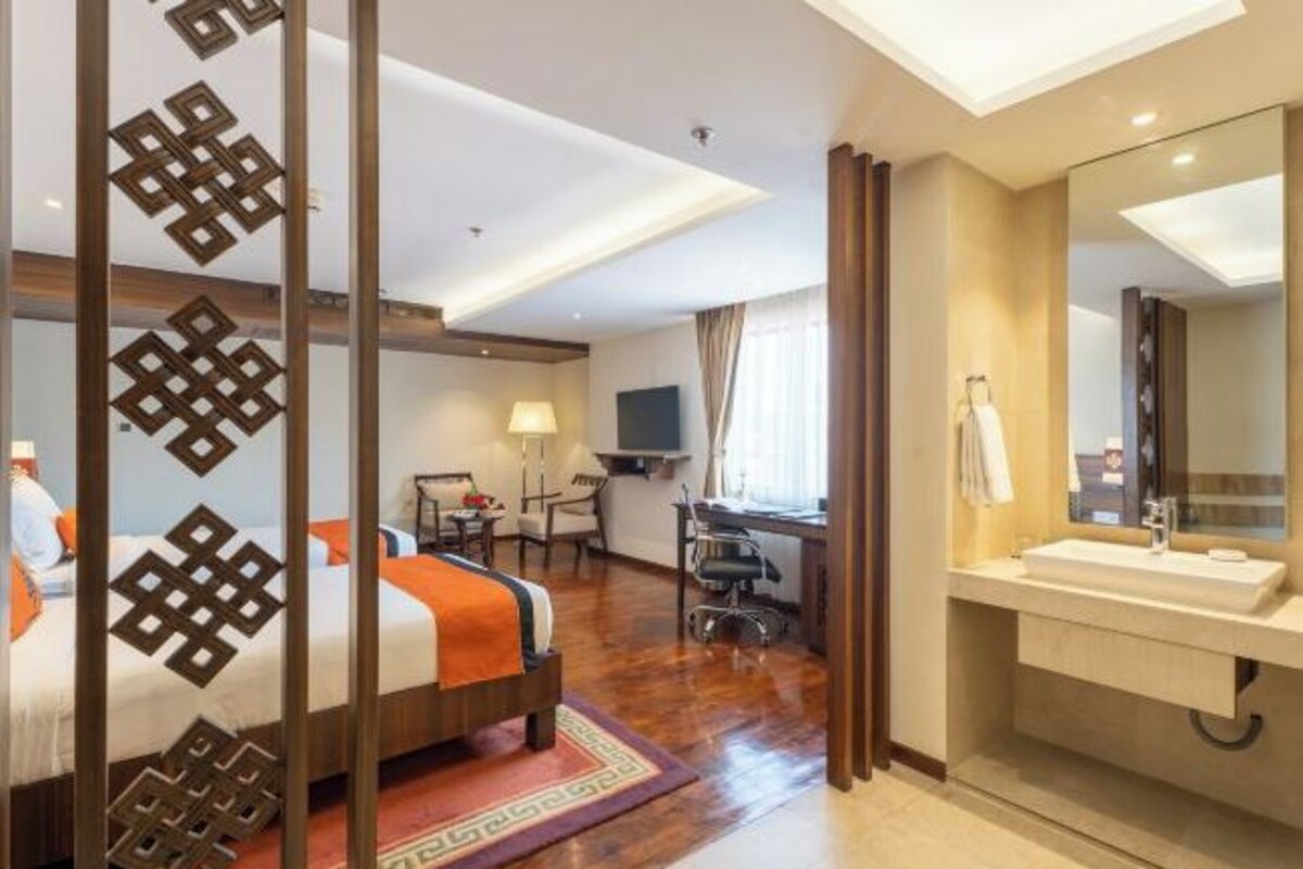 A hotel room with a bed, desk, chair, TV, and bathroom.