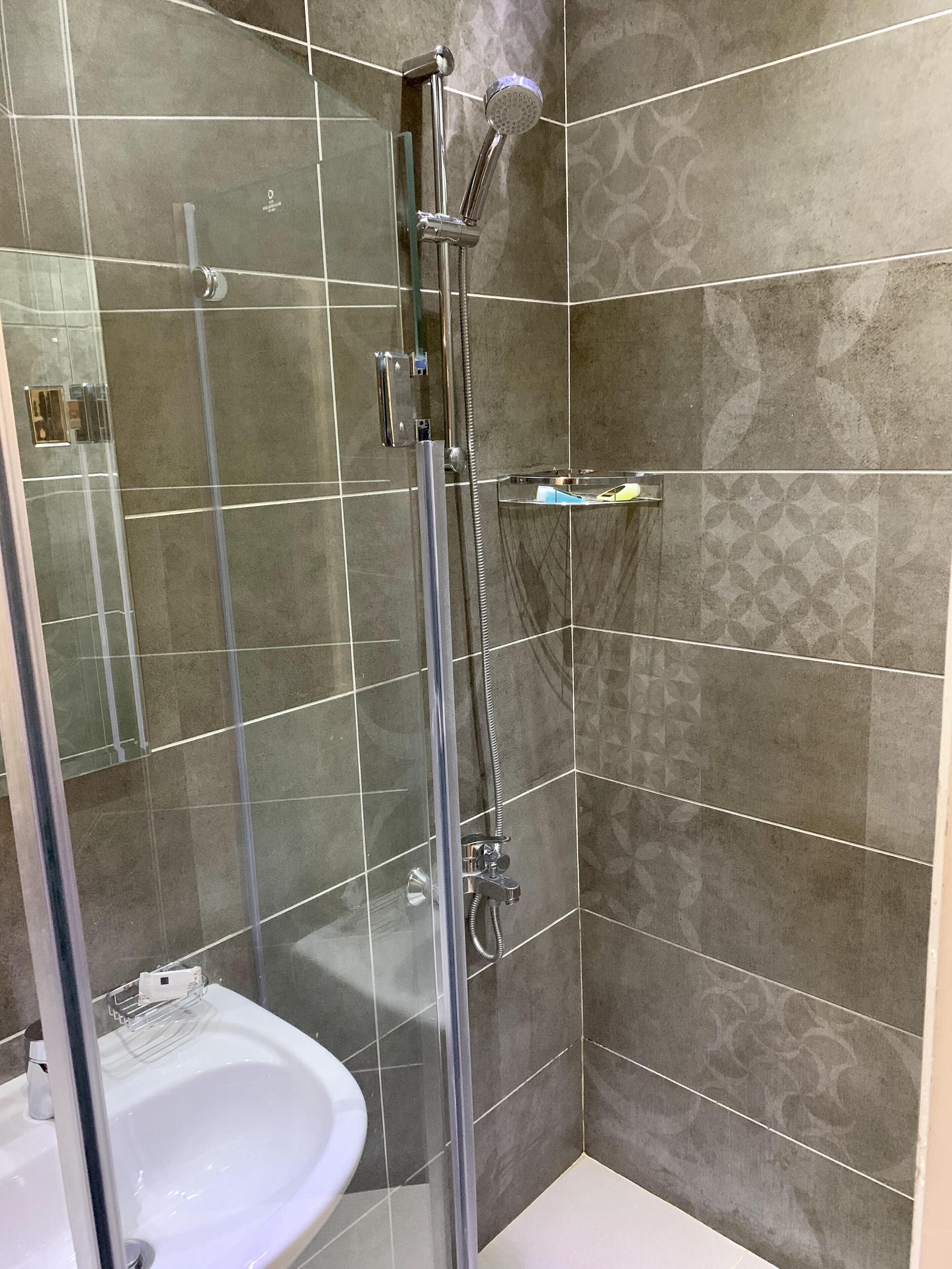 A modern bathroom with a glass-enclosed shower, a white sink, and patterned tiles.