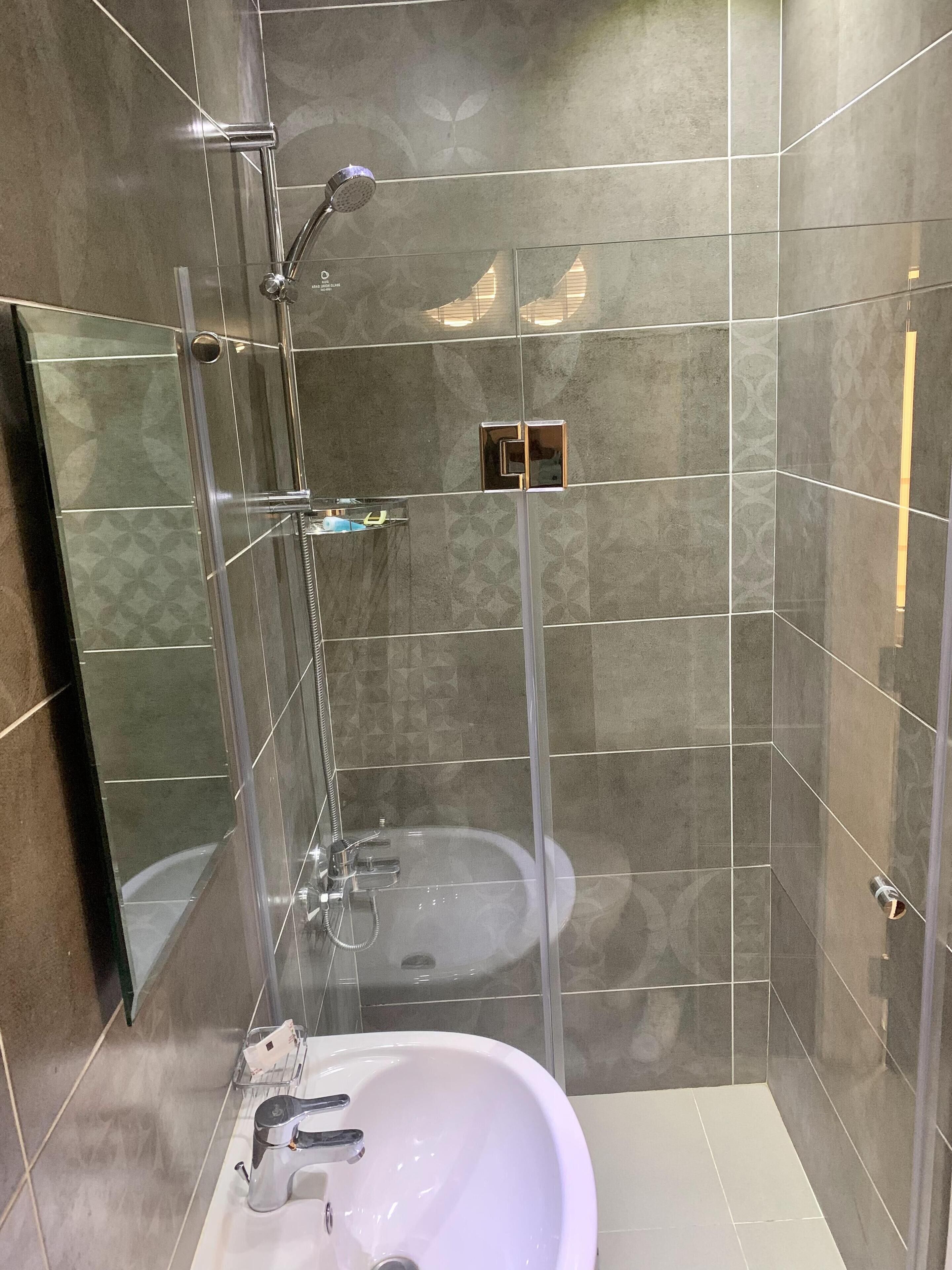 A modern bathroom with a glass-enclosed shower, a white sink, and a mirror.