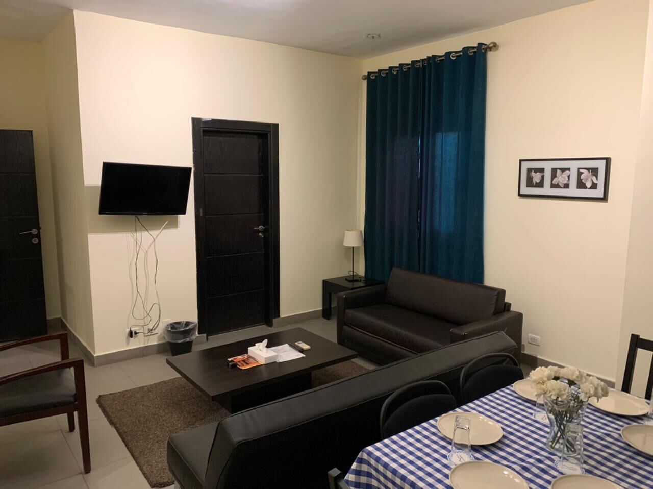 A living room with a sofa, coffee table, TV, and a dining area with a table set for two.
