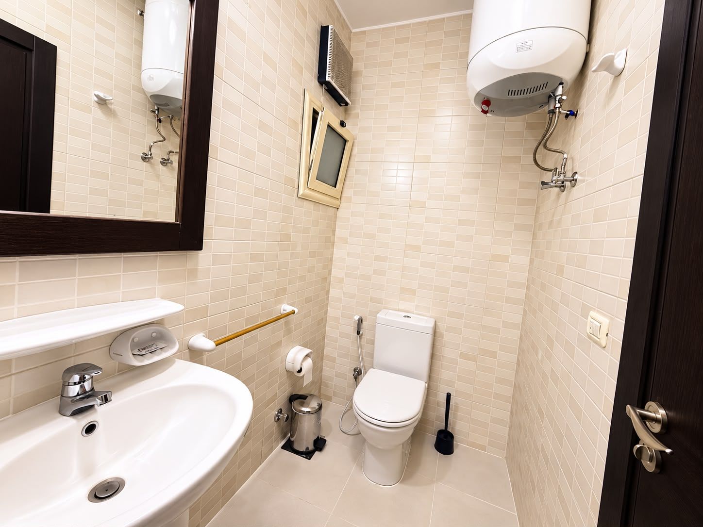 A bathroom with a sink, toilet, and a shower head.