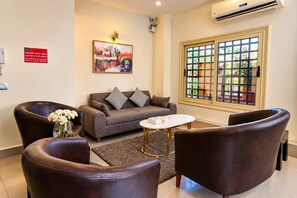 A modern living room with a sofa, two armchairs, a coffee table, and a painting on the wall. - Sakan 275 (New Cairo)