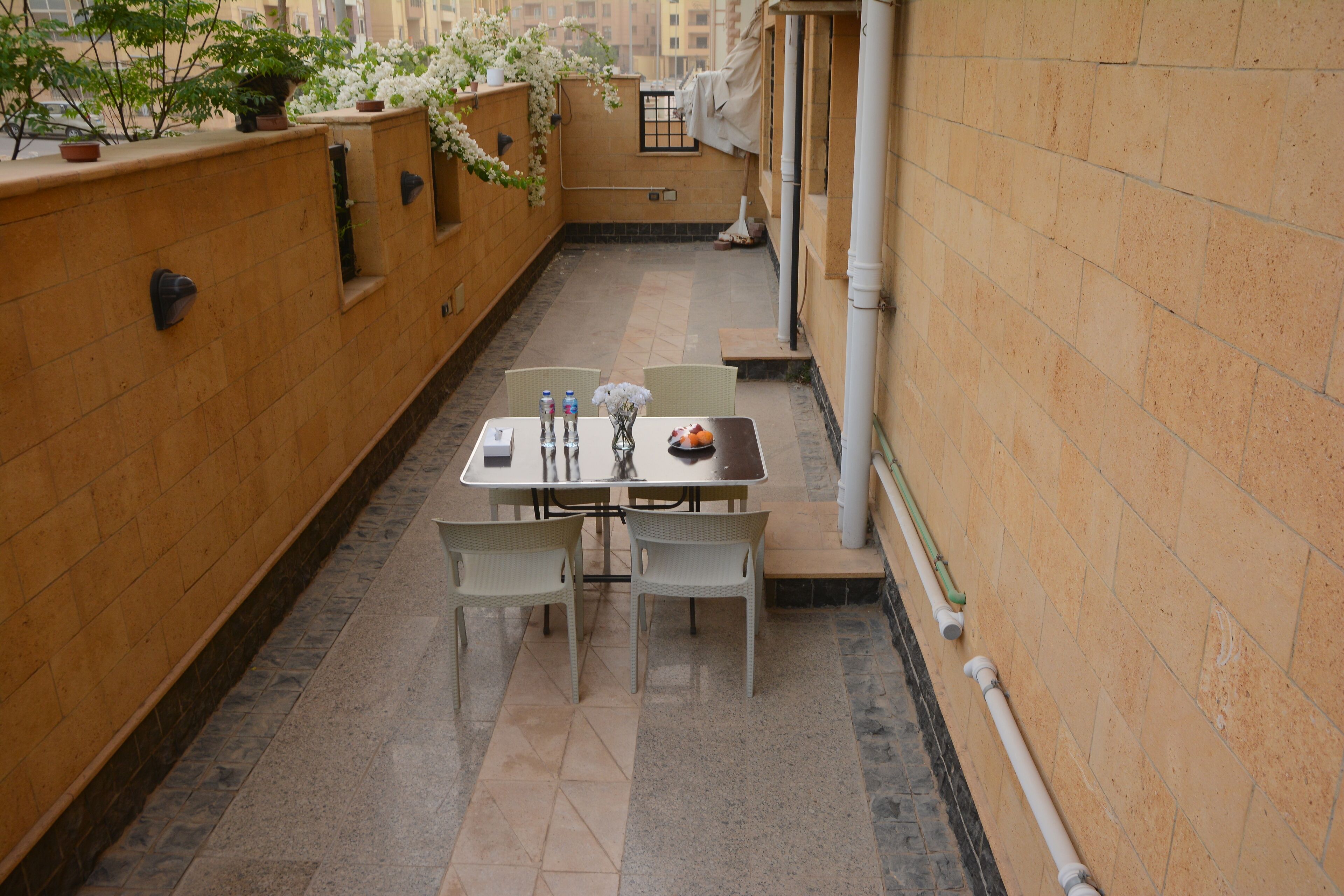 A small, enclosed patio area with a table and chairs, a potted plant, and a view of the cityscape.