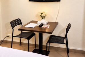 A hotel room with a single table, two chairs, a remote control, a tissue box, and a vase with flowers. - Sakan 275 (New Cairo)