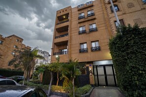 Un immeuble résidentiel à plusieurs étages, doté de balcons, d’une entrée sécurisée et entouré de verdure.