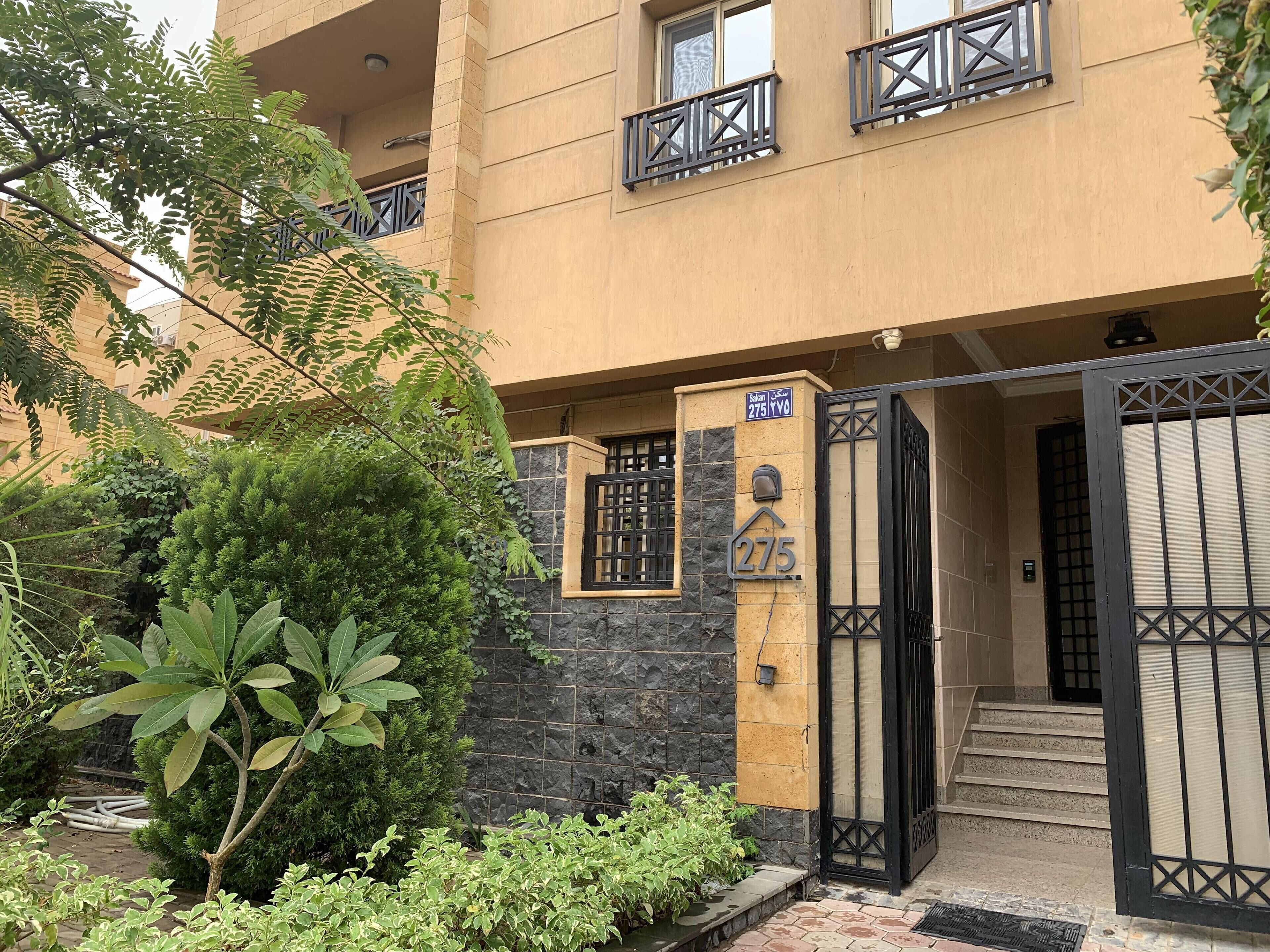 A residential building with a stone facade, a gated entrance, and a staircase leading to the entrance.