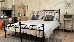 A bedroom with a bed, a fireplace, a nightstand, and a wall-mounted shelf. - Home Sweet Home (Gallicano nel Lazio)