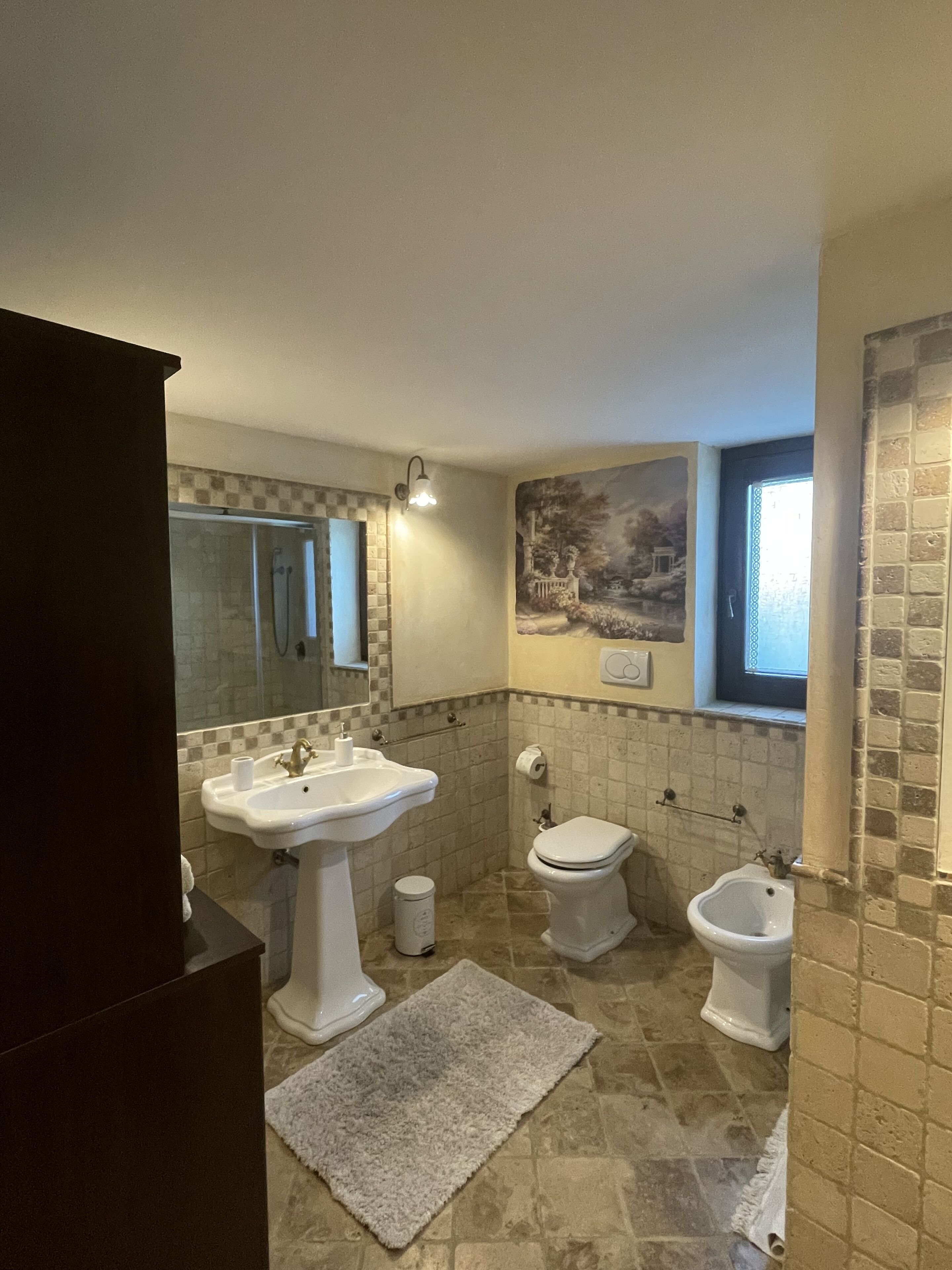 A bathroom with a sink, toilet, bidet, and a mirror.