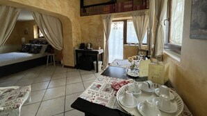 A cozy room with a bed, a table set for tea, and a bookshelf. - Home Sweet Home (Gallicano nel Lazio)