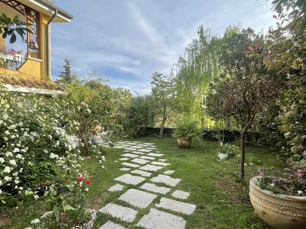 Un jardin avec un chemin de pierres menant à un bâtiment à la façade jaune.