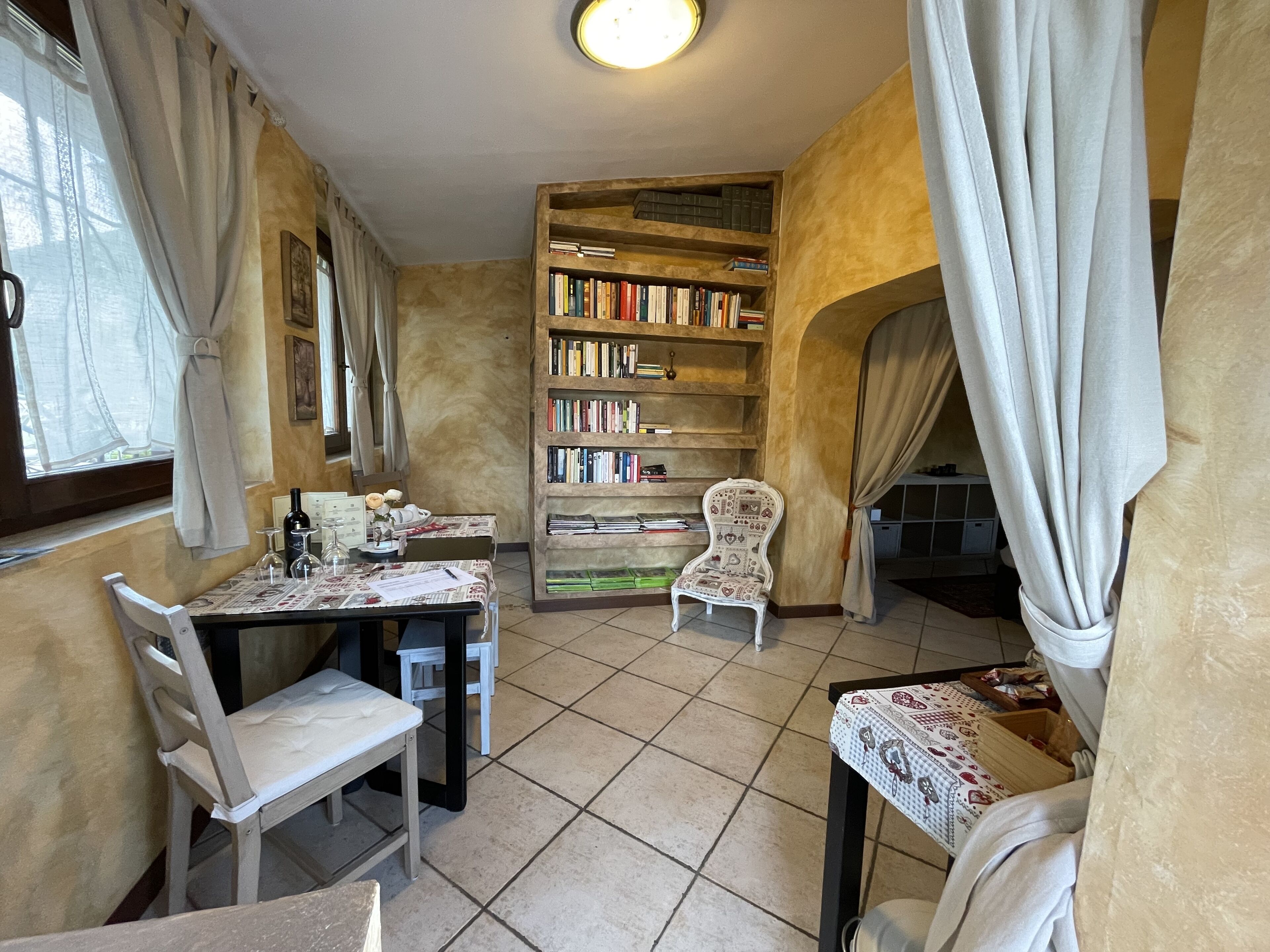 A cozy reading nook with a bookshelf, two chairs, and a table with a floral tablecloth.