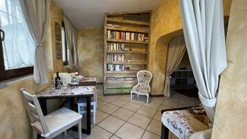 A cozy reading nook with a bookshelf, two chairs, and a table with a floral tablecloth.