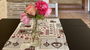 A kitchen with a central island, a dining table with a patterned tablecloth, and a vase with flowers. - Home Sweet Home (Gallicano nel Lazio)