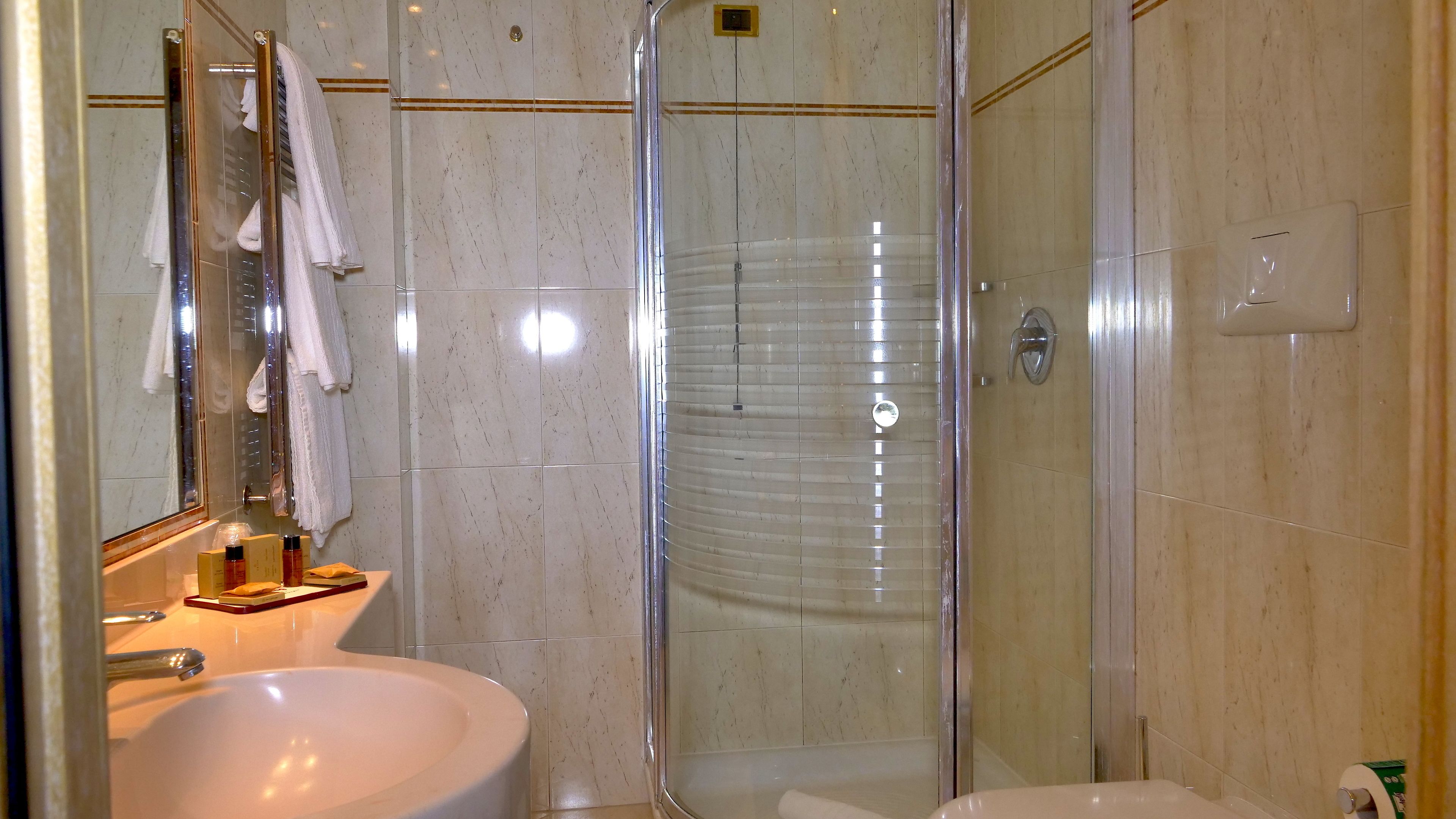 Un bagno moderno con cabina doccia in vetro, lavabo con articoli da toilette e specchio.