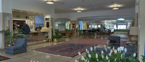 Un vestíbulo amplio con mostrador de recepción, zona de estar y área de comedor.