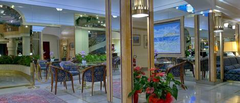 A lobby with a central seating area, a staircase, and a large painting on the wall.