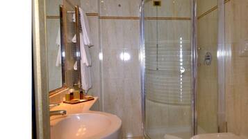Un bagno con doccia vetro, lavandino e specchio.