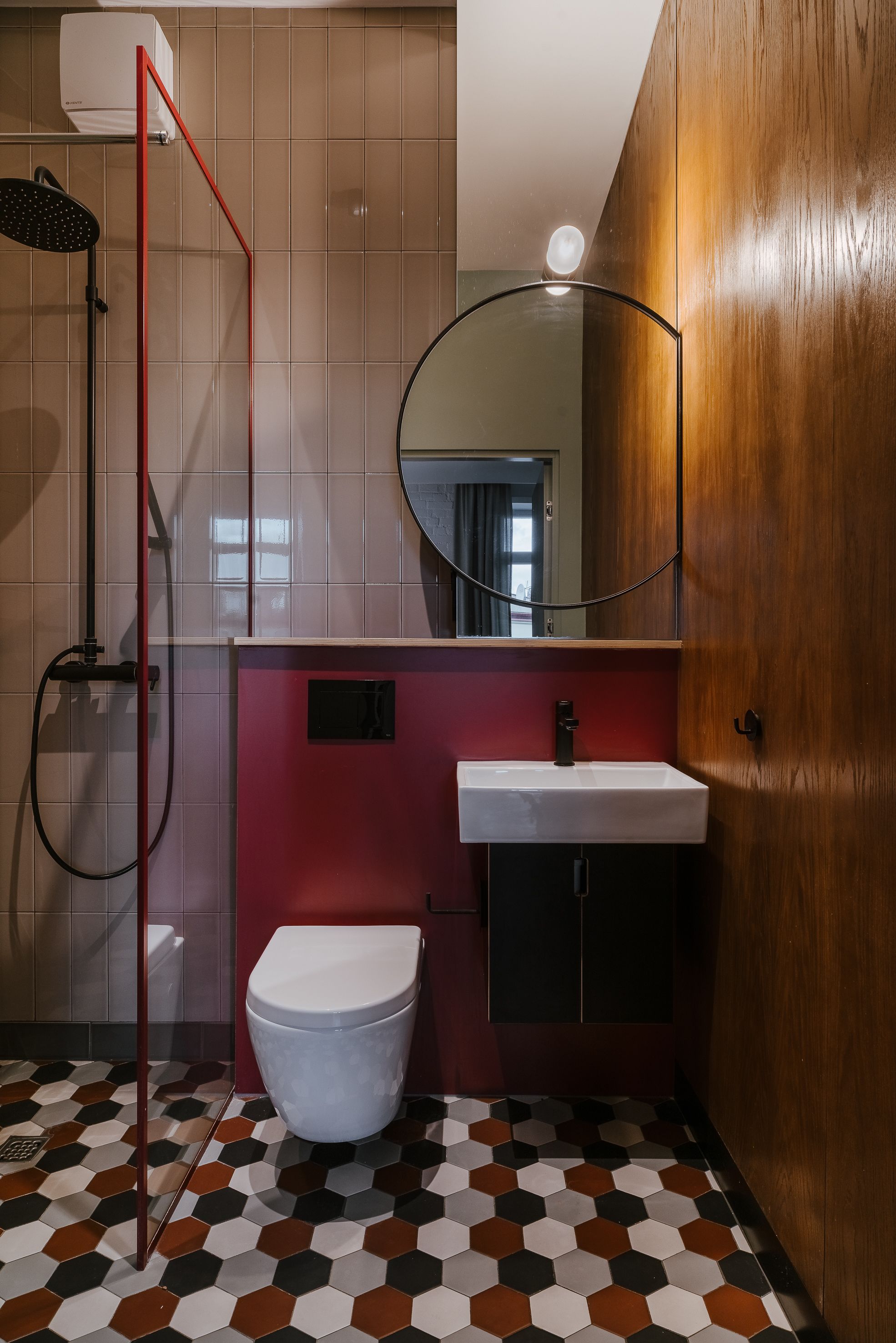A bathroom with a white toilet, a red shower enclosure, a white sink, and a wooden vanity.