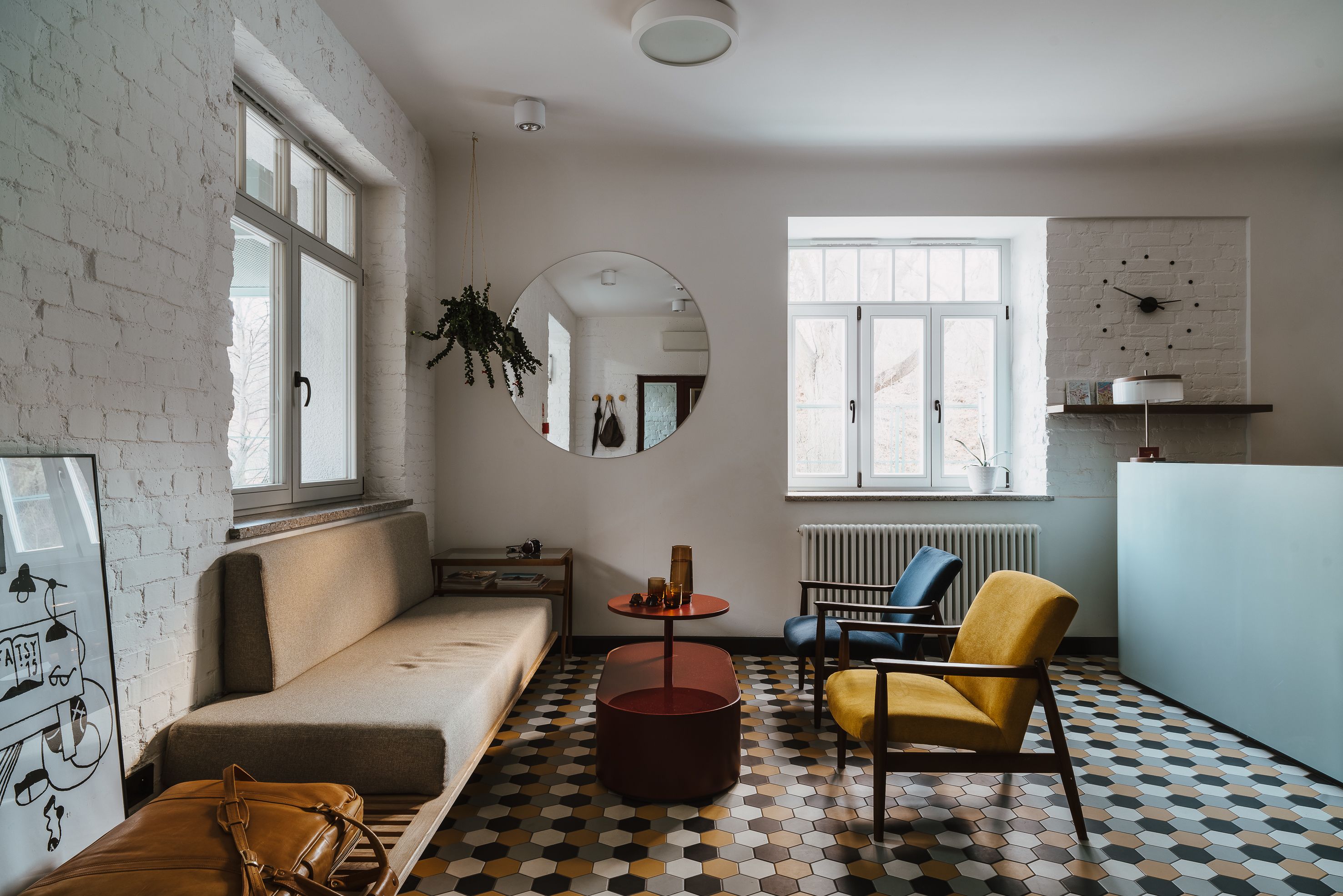 Un salon moderne avec un canapé, un fauteuil, une table ronde et un miroir.