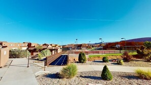 A residential area with houses, a tennis court, and a clear blue sky.
