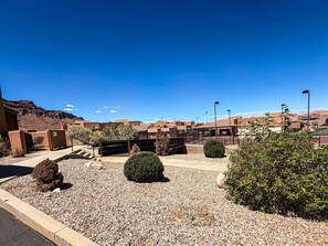 A courtyard with a gravel ground, a small fenced area, and a building with a flat roof.