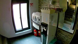 Eine kompakte Küche mit einer Mikrowelle, einem kleinen Kühlschrank und einem Fenster mit Jalousien.