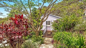 Ein Haus mit einem Steinweg, der zur Haustür führt, umgeben von üppiger Vegetation und verschiedenen Pflanzen.