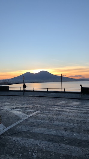 A waterfront promenade with a mountain in the background, a speed limit sign, and a railing. - B&B Palazzo Majorana (Naples)