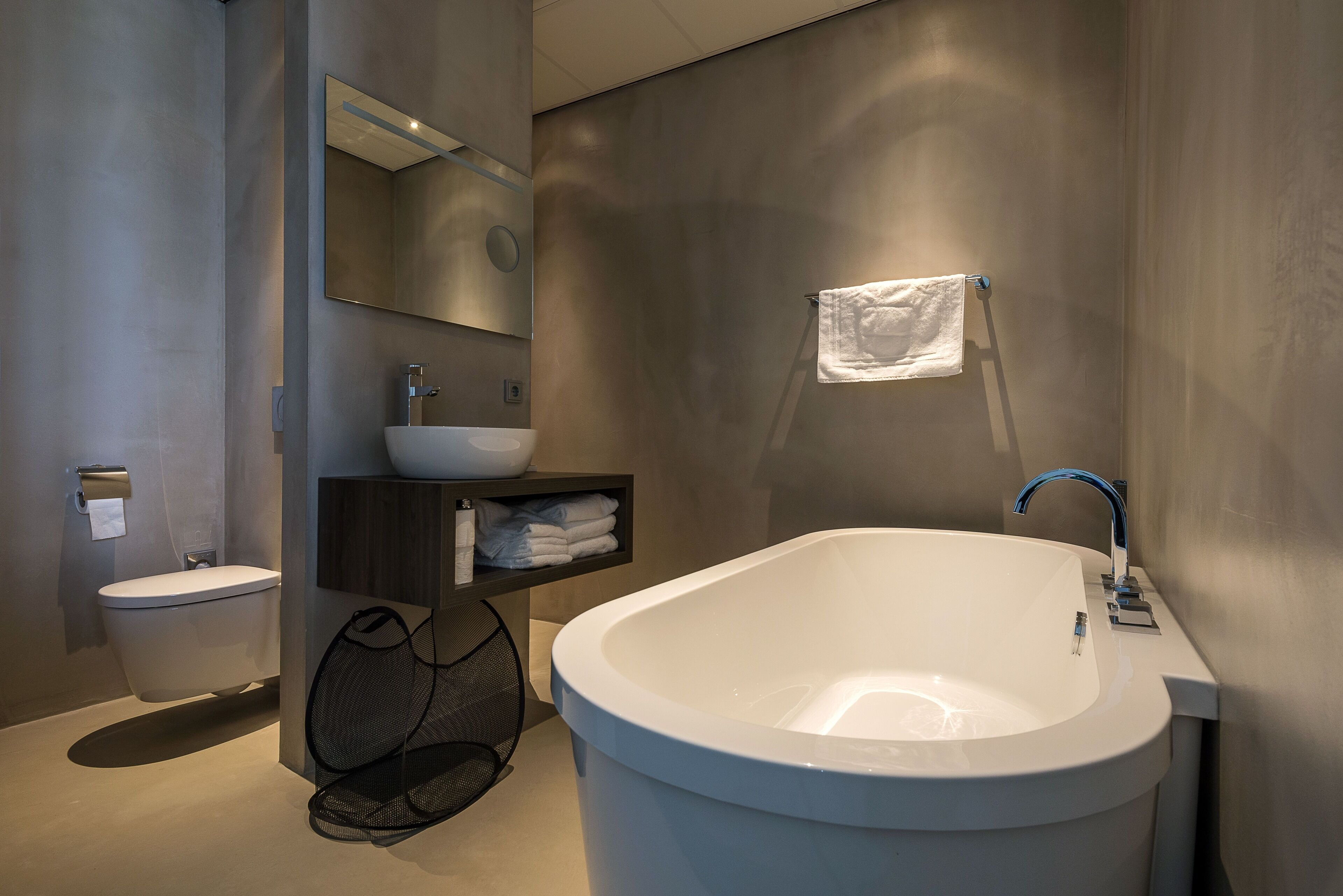 Ein modernes Badezimmer mit einer freistehenden Badewanne, einem Waschbecken, einer Toilette und einem Handtuchhalter.