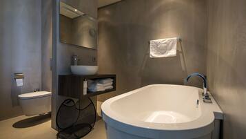 Ein modernes Badezimmer mit einer freistehenden Badewanne, einem Waschbecken, einer Toilette und einem Handtuchhalter.