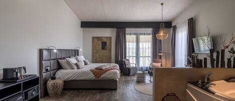Quarto moderno com uma cama grande, mesas de cabeceira, uma escrivaninha e um banheiro com pia e espelho.